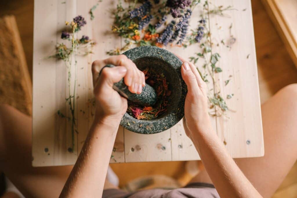 A Person Pounding Dried Flowers Using a Mortar and Pestle
