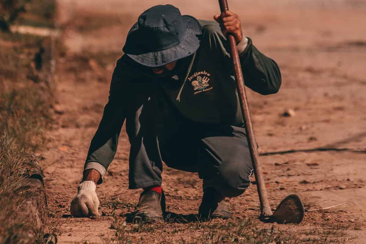 Man working on farm with hoe, hat, and gloves