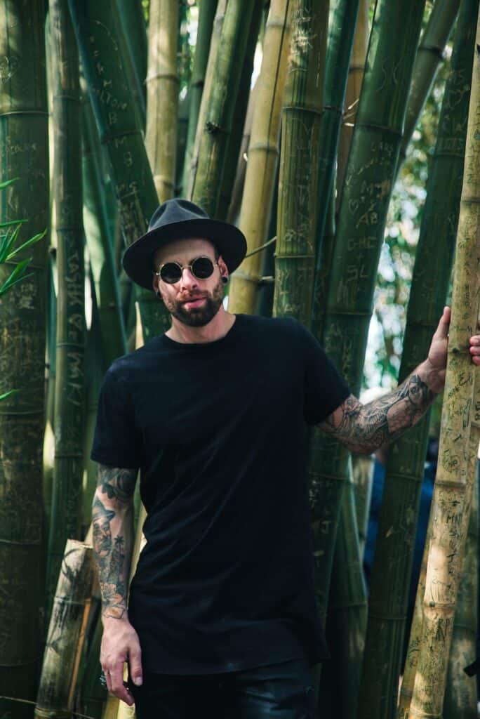 Man Holding Bamboo Plant Wearing Sunglasses and Fedora Hat