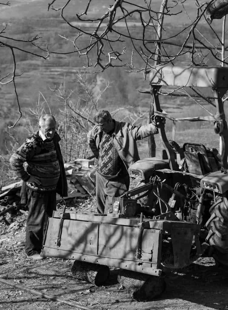 Two men are standing next to a tractor